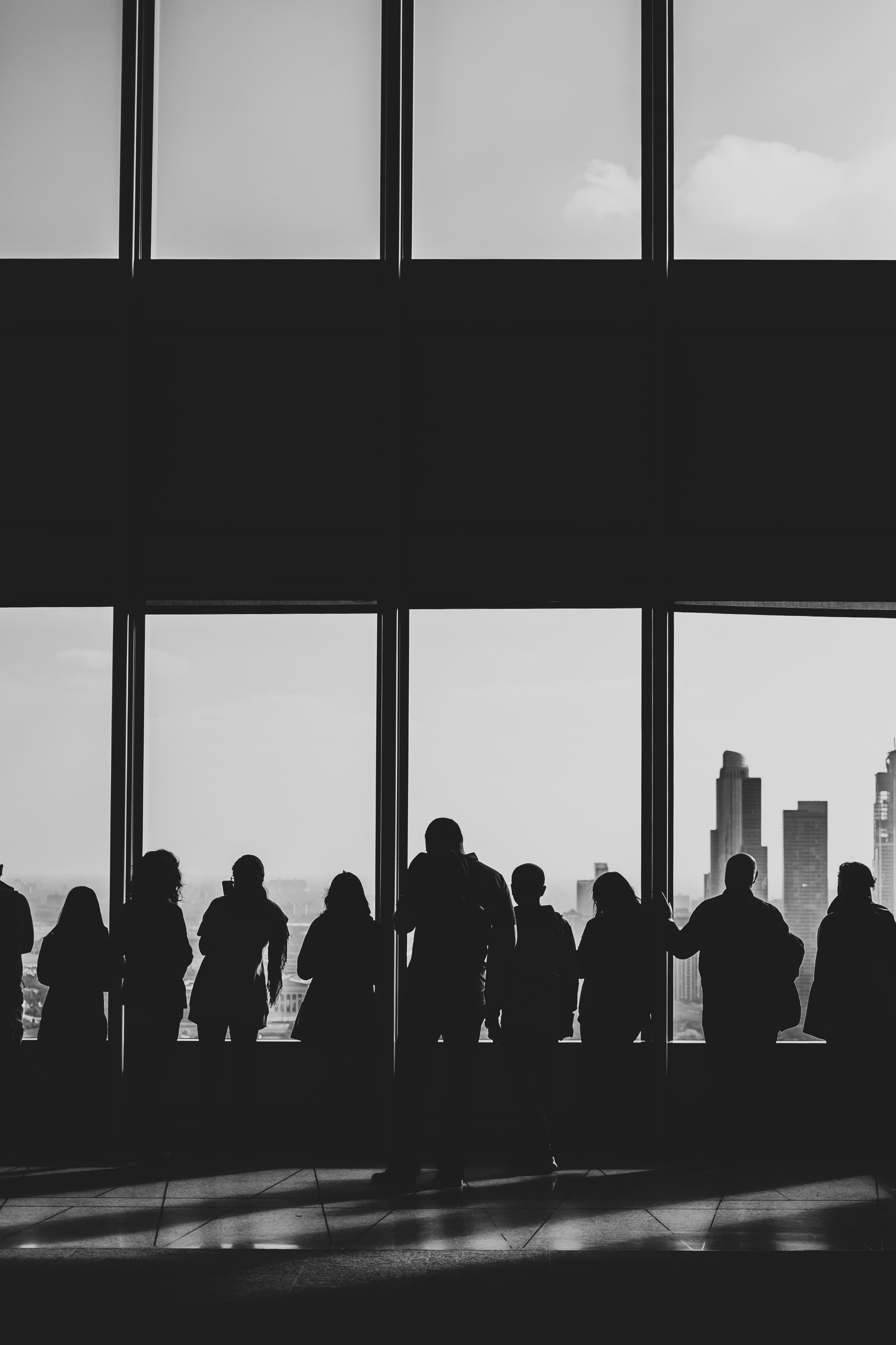 Silhouettes against floor-to-ceiling windows, a city behind them, the room still talking.